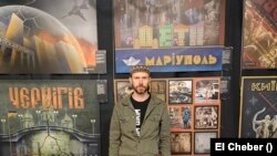 Рустем Скибин на фоне разработанных им плакатов о городах Украины, подвергшихся оккупации. Фото El Cheber